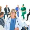 female doctor in the front with group of health professionals in a meeting behind her