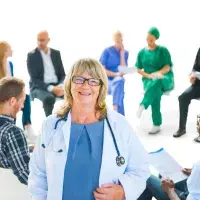 female doctor in the front with group of health professionals in a meeting behind her